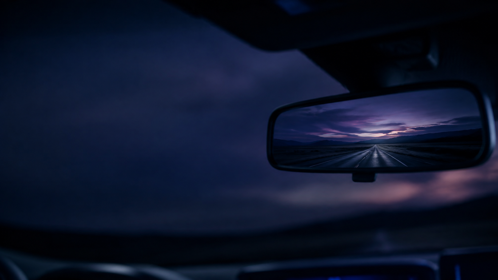 A road seen through a vehicle's rearview mirror at dusk